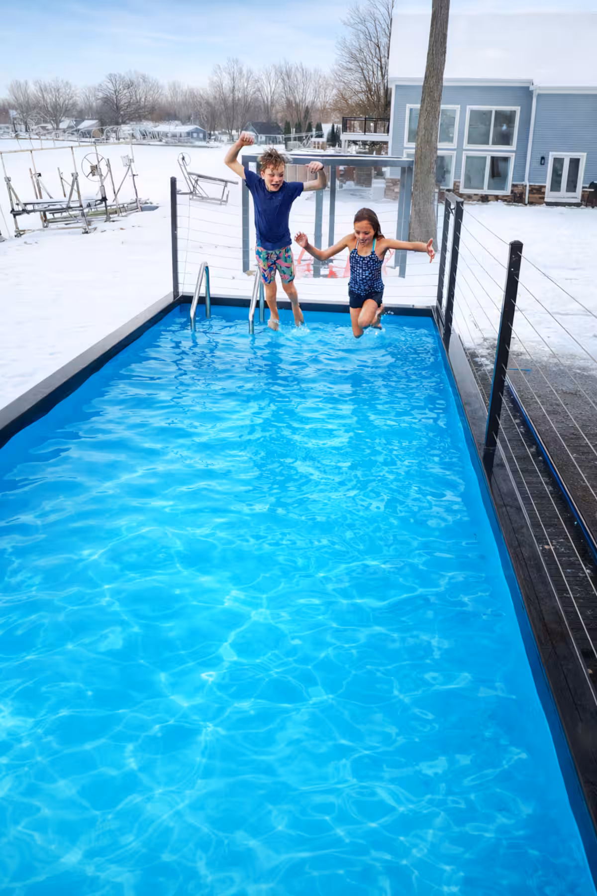 Two children jumping into the clear blue water of a container pool