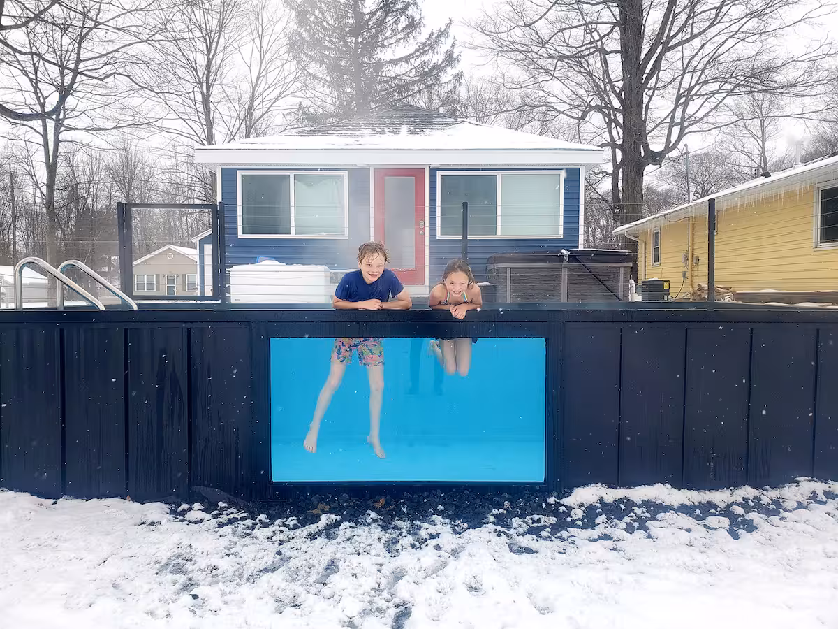 Two children looking into a container pool through its acrylic viewing window in winter