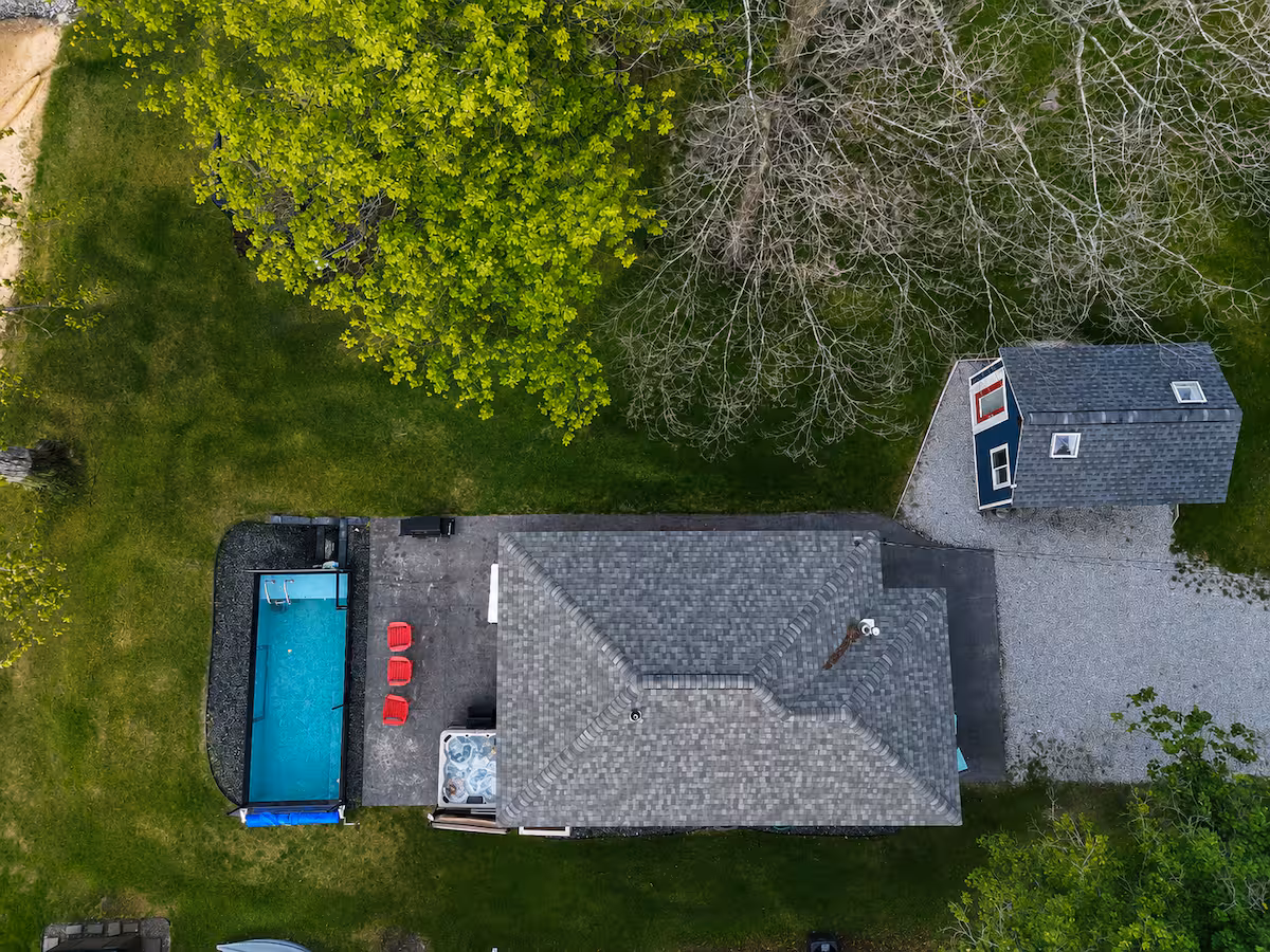 Aerial view of a black container pool and paver patio behind a short-term rental home