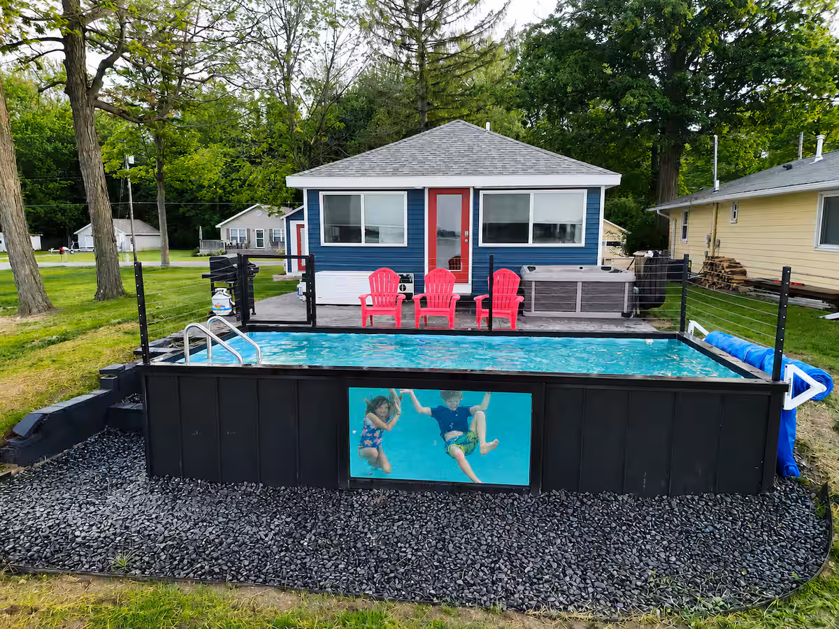 Container pool with red lounge chairs and a hot tub beside a rental home