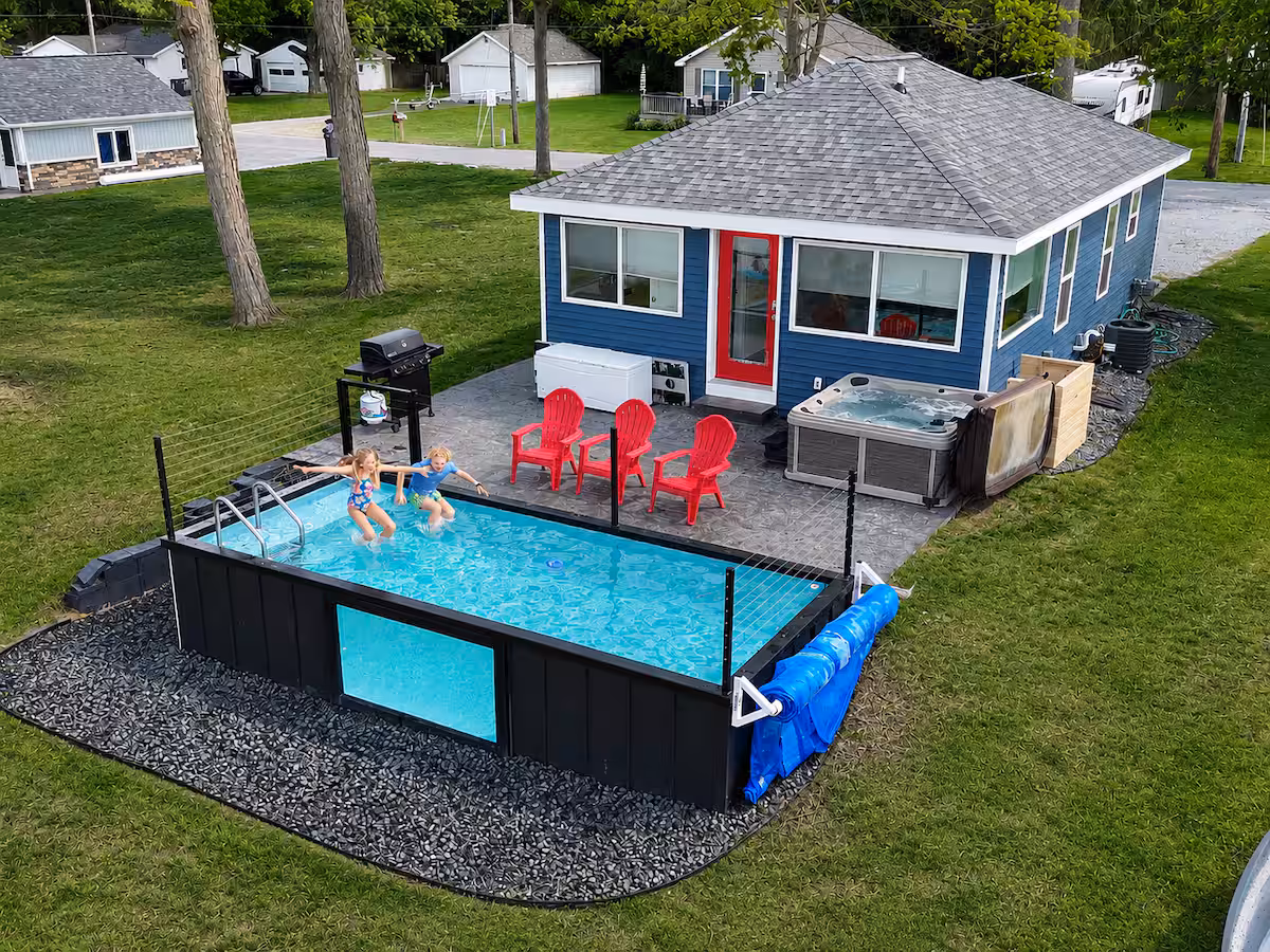 Guests swimming in a container pool behind a blue vacation rental cottage